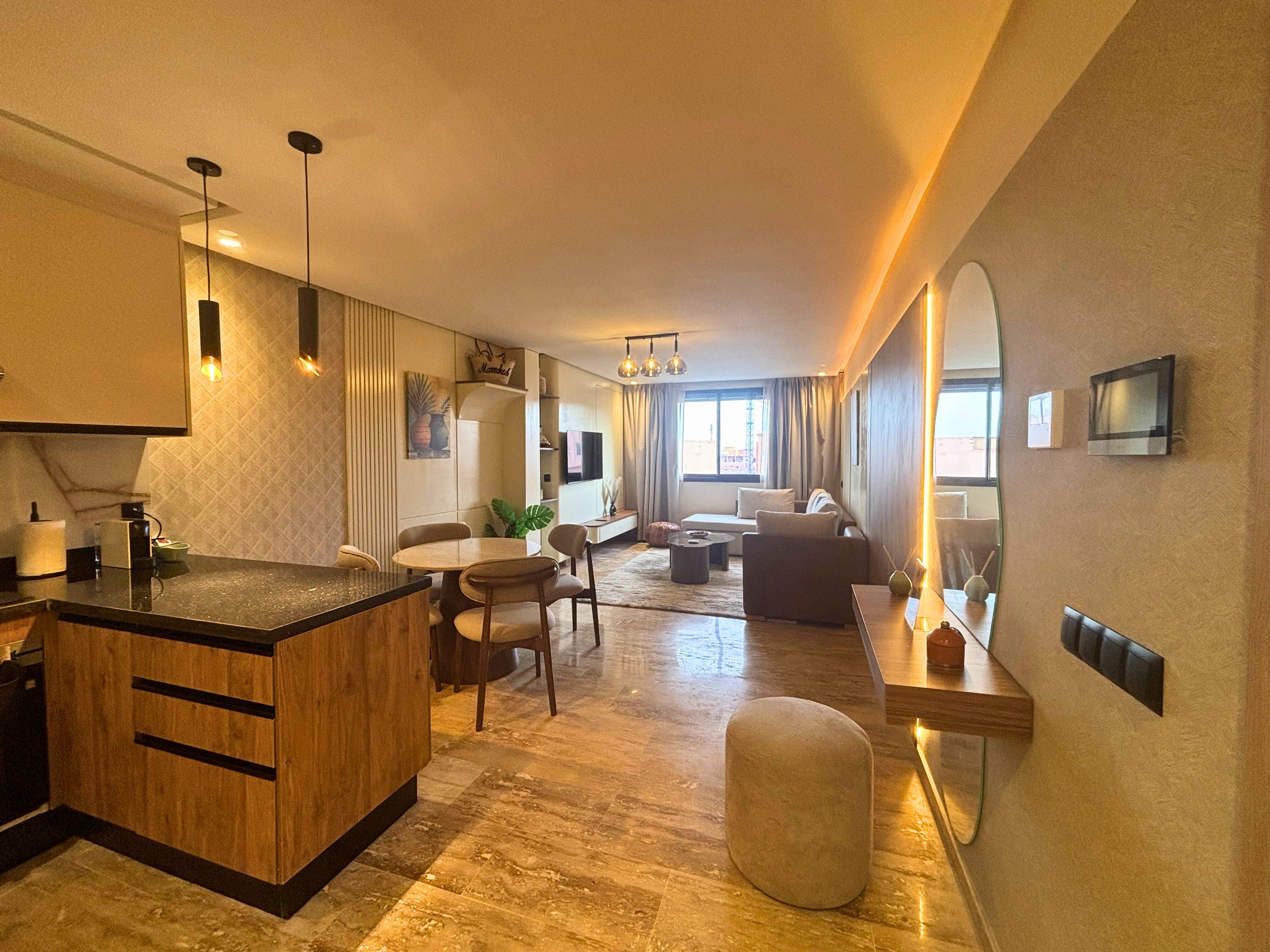 A modern living room with a dining area, a kitchen with a wooden island, and a large mirror on the wall.