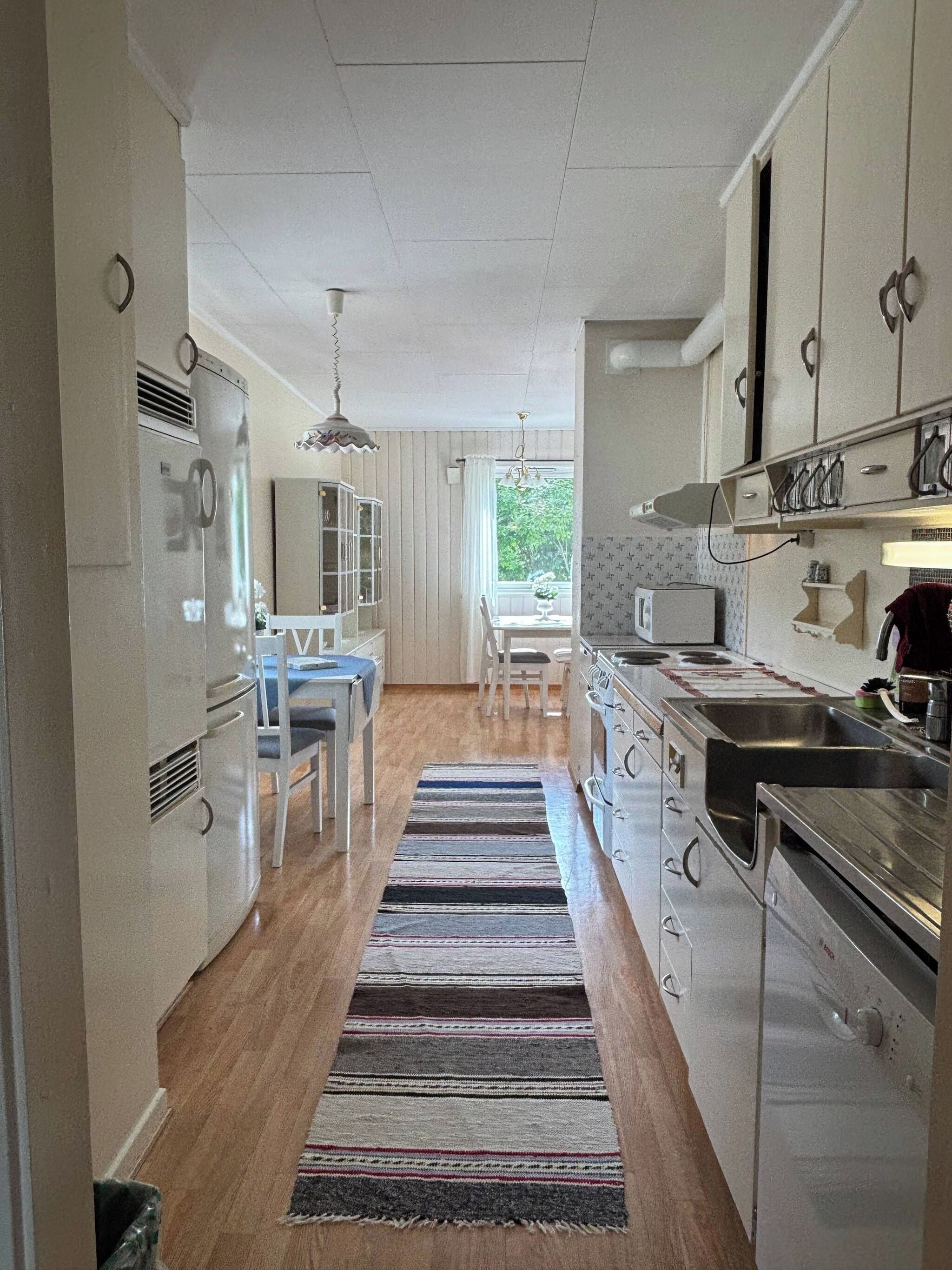 A kitchen with a central island, stainless steel appliances, and a window with a view.