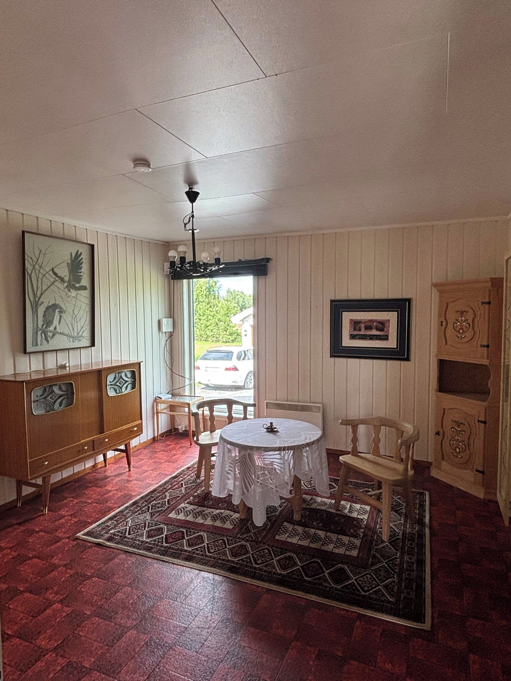 A room with a round table, chairs, a cabinet, and a rug.