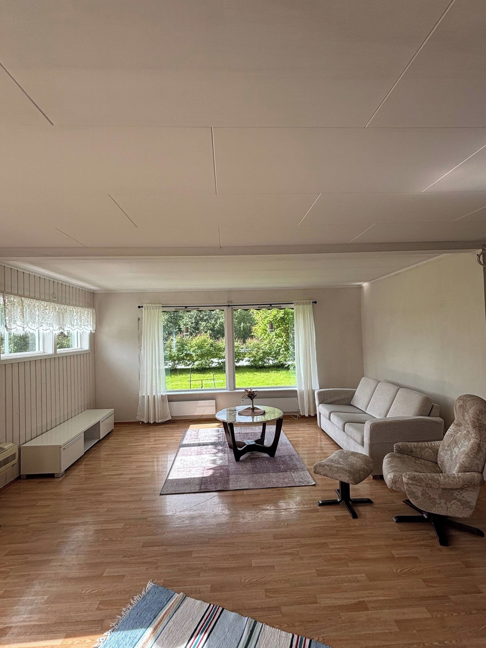 Una sala de estar amplia con un sofá, un sillón y una mesa de centro.