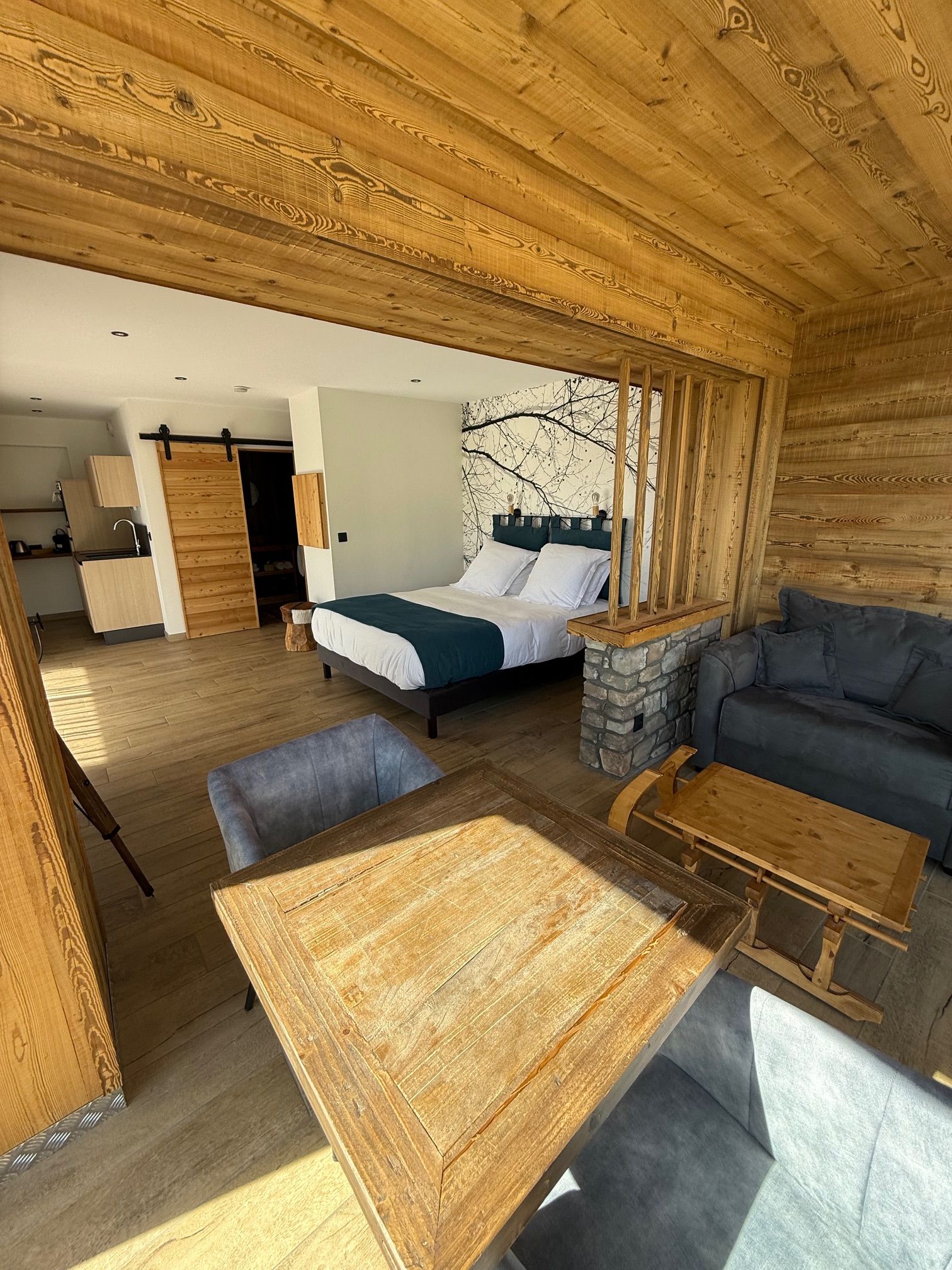 L'intérieur d'un chalet en bois, avec un lit, un canapé et une table à manger.