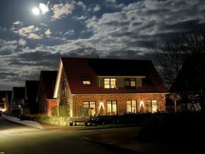 A two-story house with a red-tiled roof, multiple windows, and a well-lit front porch. - Holiday Home in Juist With Swimming Pool (Juist)