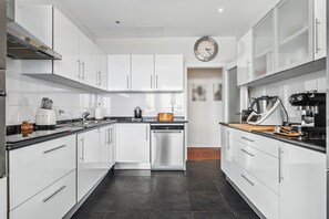 A modern kitchen with white cabinets, a black countertop, and stainless steel appliances.