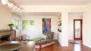 Une pièce comprenant une table à manger, un canapé, une cheminée et un grand tableau au mur.