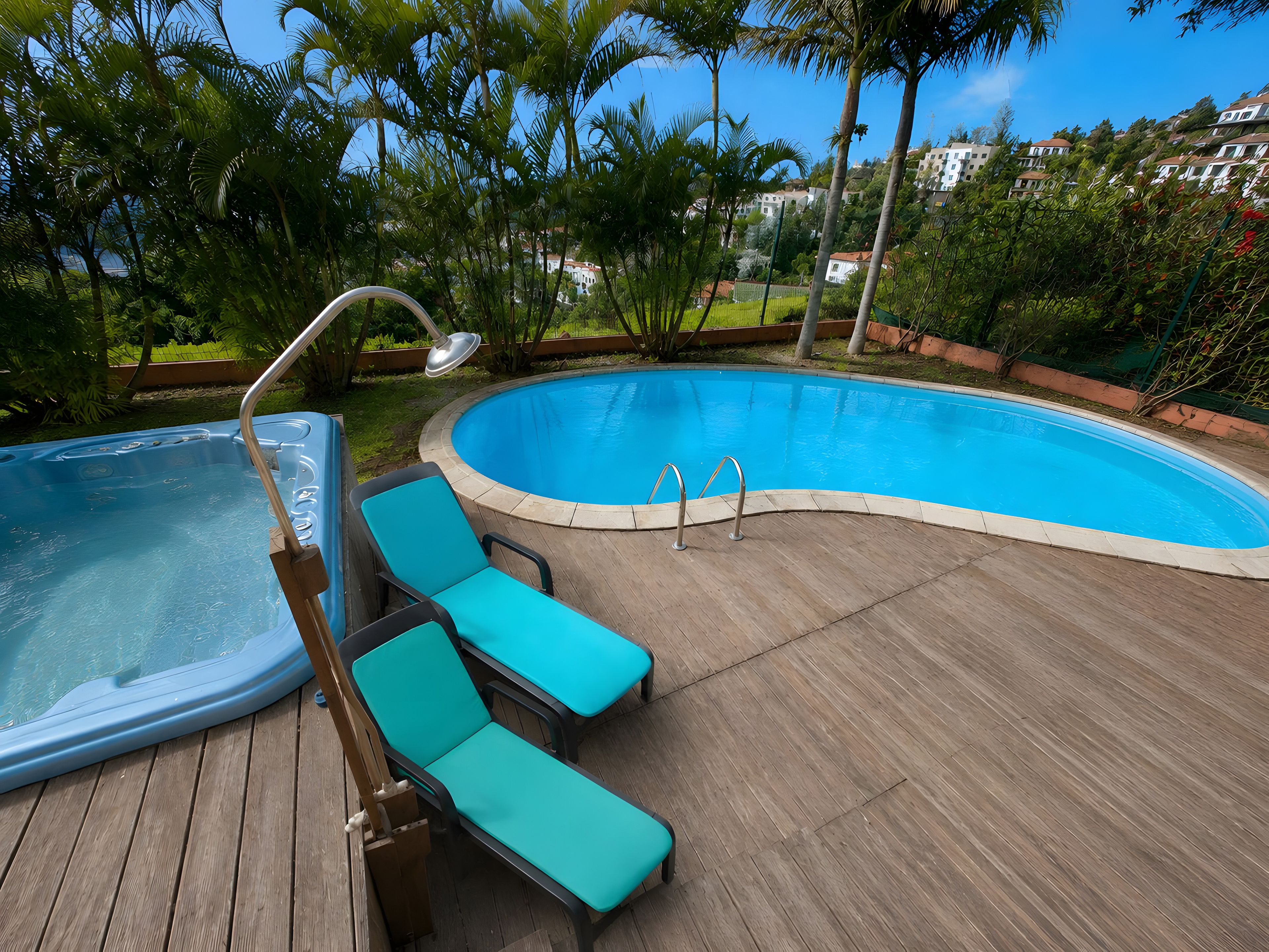 A swimming pool with a wooden deck, lounge chairs, and a hot tub.