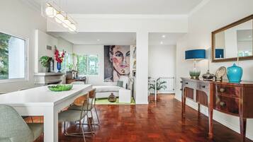 A modern interior with a dining area, a large painting, and a wooden floor.