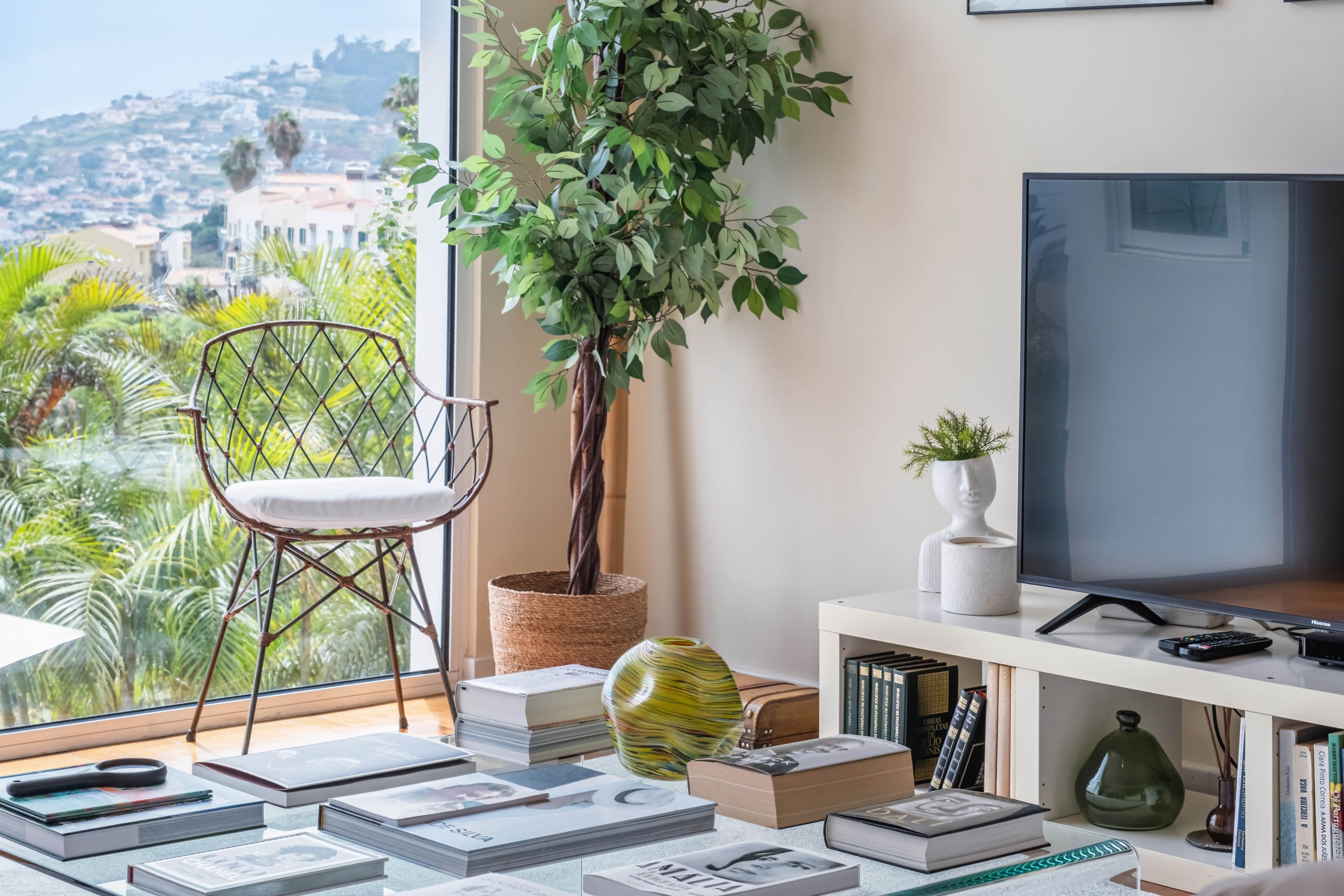 Ein modernes Wohnzimmer mit großem Fenster, einem Fernseher und einer Bücherwand voller Bücher.