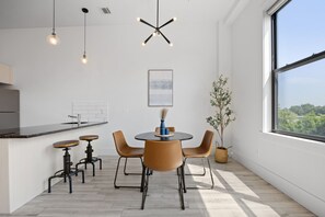 A modern kitchen with a dining area, a large window, and a view of greenery. - Near NYC High-End Kearny Loft w/ Gym & Patio (Kearny)