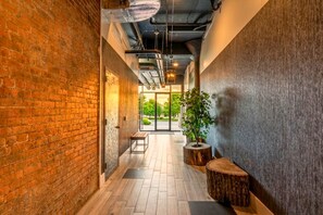 A corridor with a brick wall, a bench, a potted plant, and a wooden stump. - Near NYC High-End Kearny Loft w/ Gym & Patio (Kearny)