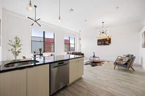 Une cuisine spacieuse dotée d’un grand îlot central, de luminaires suspendus modernes et offrant une vue sur la ville grâce à de grandes fenêtres.