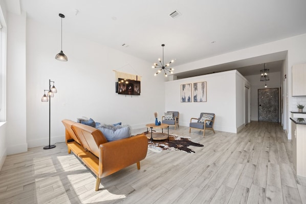 A spacious living area with a sofa, chairs, a coffee table, and a fireplace. - Near NYC High-End Kearny Loft w/ Gym & Patio (Kearny)