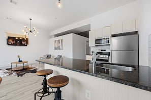A modern kitchen with a central island, stainless steel appliances, and a seating area with a round table and stools. - Near NYC High-End Kearny Loft w/ Gym & Patio (Kearny)