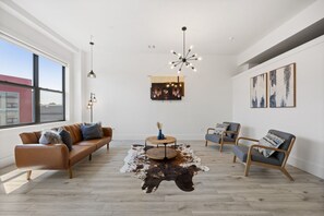 A modern living room with a leather sofa, a round coffee table, and two armchairs. - Near NYC High-End Kearny Loft w/ Gym & Patio (Kearny)