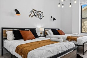 Ein modernes Hotelzimmer mit zwei Betten, einer Wanddekoration und einem Fenster mit Jalousien.