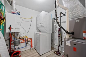Ein Hauswirtschaftsraum mit Warmwasserbereiter, einer weißen Waschmaschine sowie verschiedenen Rohren und Schläuchen.