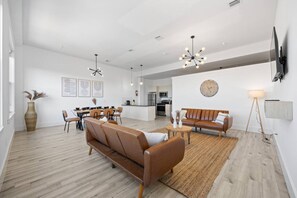 Uma sala ampla com sofá, mesa de jantar e cozinha ao fundo.