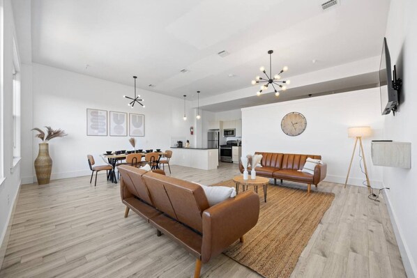 A spacious living area with a sofa, a dining table, and a kitchen in the background. - Luxury Stay for Groups Near NYC - Gym & Patio (Kearny)