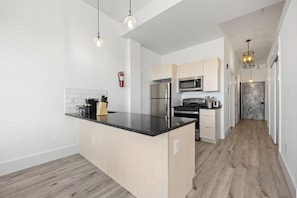 A modern kitchen with a central island, stainless steel appliances, and pendant lighting. - Luxury Stay for Groups Near NYC - Gym & Patio (Kearny)