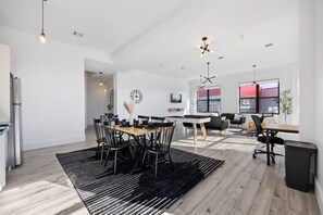 A modern interior with a dining area, seating, and a large window. - Huge Top-Floor 2BR, NYC View, Patio & Gym (Kearny)