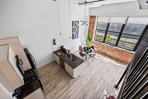 A modern kitchen with a central island, dining area, and large windows. - Signature Rustic 2BR Near NYC Pets, Gym & Parking (Kearny)