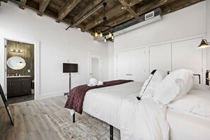 Ein Schlafzimmer mit Bett, Fernseher, Kleiderschrank und einem Badezimmer mit Spiegel und Waschbecken.