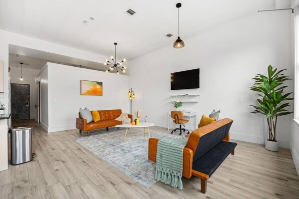 Una sala de estar moderna con un sofá, una mesa de centro y un televisor montado en la pared.