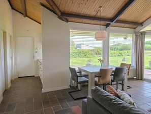 A modern interior with a dining area, a sofa, and a view of a garden. - Holiday Home in Zoutelande With Barbecue (Zoutelande)