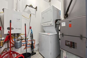 Ein kleiner Hauswirtschaftsraum mit Warmwasserbereiter, Waschmaschine sowie verschiedenen Rohren und Schläuchen.
