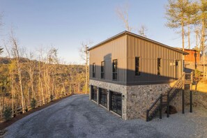 Ein modernes, zweistöckiges Gebäude mit Steinunterbau, großen Fenstern und einer Holzterrasse.