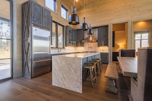 Una cocina moderna con una isla central, electrodomésticos de acero inoxidable y taburetes de bar.