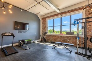 A gym with exercise equipment, a treadmill, a stationary bike, and a large window with a view. - Colorful Loft Gym, Patio + Parking Near NYC (Kearny)