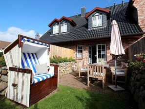 A house with a brick exterior, a tiled roof, and a patio area with outdoor furniture. - Holiday Home in Sylt With 3 Bedrooms (Sylt)