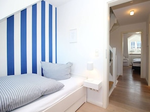 A bedroom with a bed, a bedside table, and a wall with vertical stripes. - Holiday Home in Sylt With 3 Bedrooms (Sylt)
