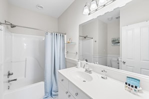 Un baño moderno con bañera, ducha, tocador con lavamanos y un espejo grande.