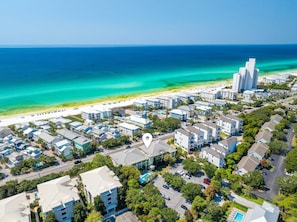 Un área residencial costera con propiedades frente al mar, un océano azul claro y una combinación de edificios de una y varias plantas.