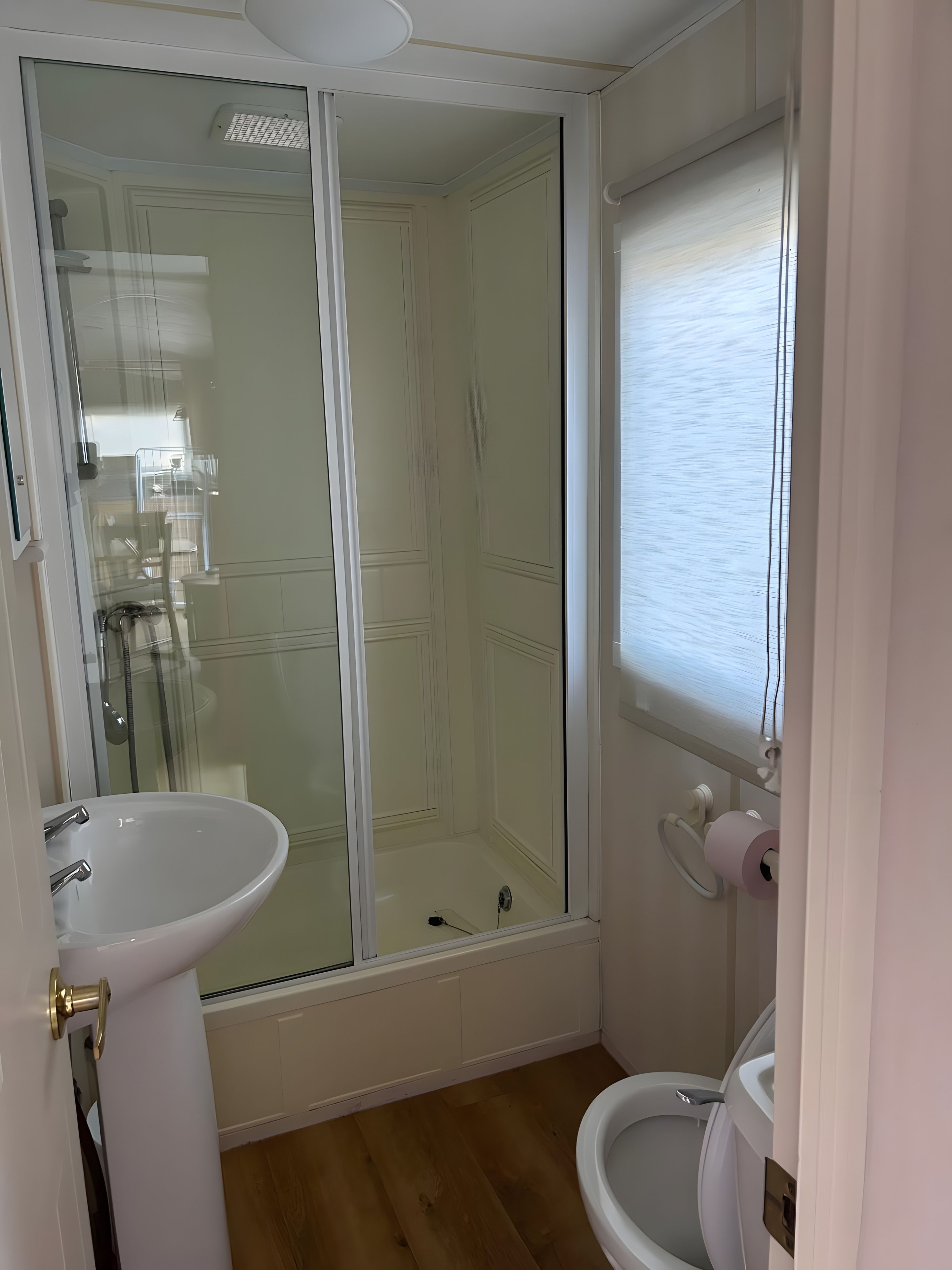 A bathroom with a glass-enclosed shower, a white sink, and a toilet.