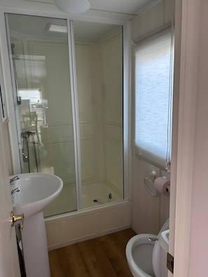A bathroom with a glass-enclosed shower, a white sink, and a toilet.