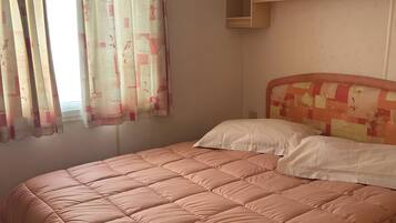 Ein Schlafzimmer mit einem Bett, einem Fenster mit Vorhängen, einer Deckenleuchte und einem Kleiderschrank.