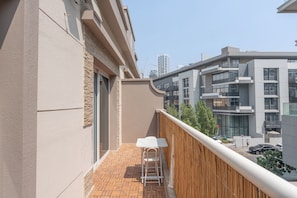 A balcony with a white table and chairs, a wooden fence, and a view of modern buildings. - StayShort - Spacious 11-Bedroom Villa Stay at Casa Royale, JVC (JVC)