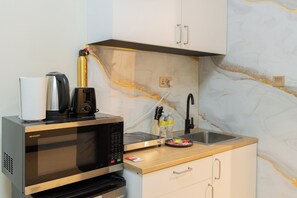 A kitchen with a flatbed microwave, a coffee maker, and a kettle. - StayShort - Spacious 11-Bedroom Villa Stay at Casa Royale, JVC (JVC)
