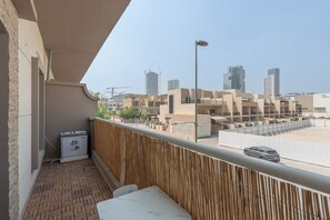 Een balkon met uitzicht op een woonwijk, een prullenbak en een tafel.