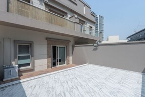 A modern building with a flat roof, a balcony, and a door leading to an interior space. - StayShort - Spacious 11-Bedroom Villa Stay at Casa Royale, JVC (JVC)