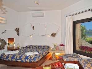 Ein Hotelzimmer mit Bett, kleinem Tisch, Fenster mit Blick und Wand-Klimaanlage.