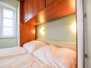 A bedroom with two beds, wooden headboard, a window with curtains, and a wall-mounted light fixture. - Villa in Kras With Swimming Pool (Dobrinj)