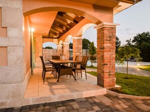 An outdoor patio with a brick column, a table with chairs, and a stone wall in the background. - Villa in Kras With Swimming Pool (Dobrinj)