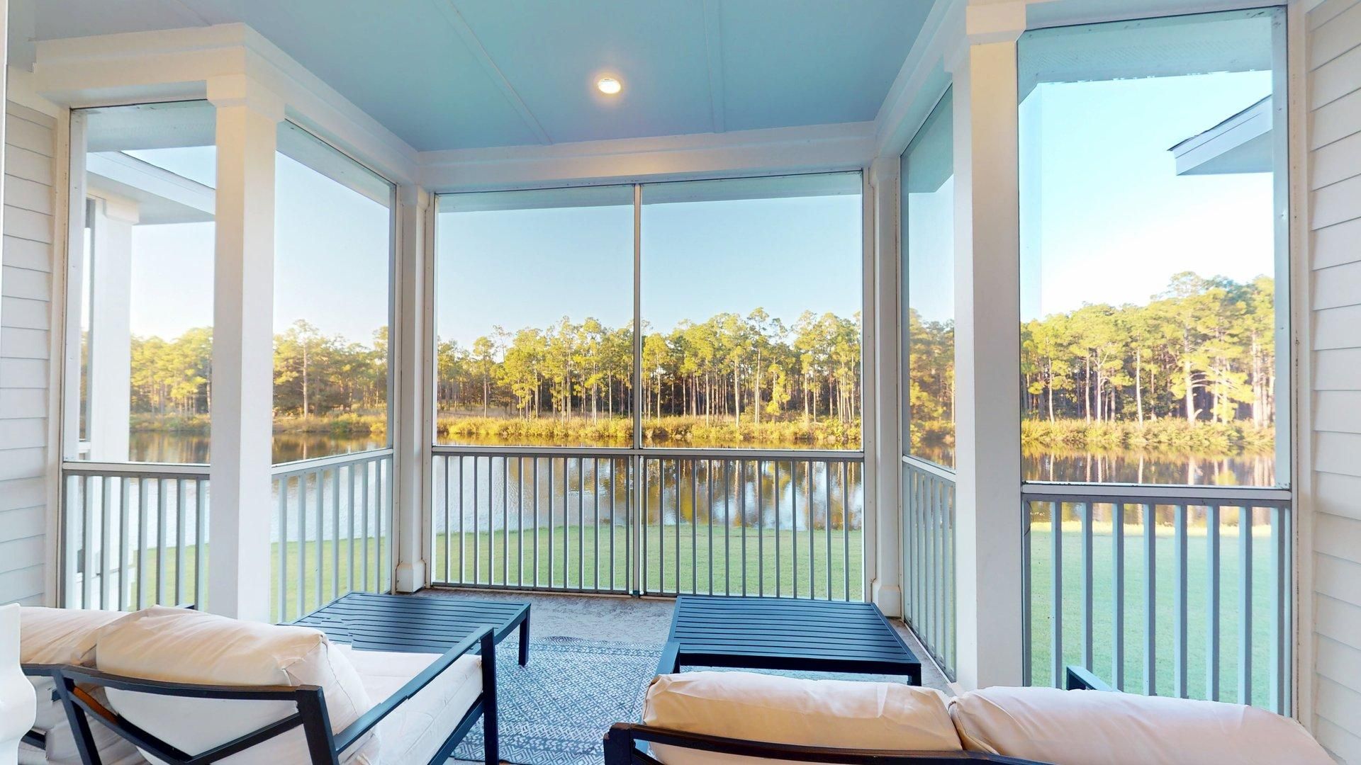 A covered outdoor seating area with a view of a lake and forest.