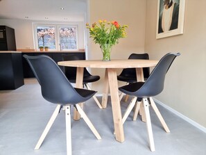 A dining area with a round wooden table and four black chairs with wooden legs. - Holiday Home in Aagtekerke With Wi-fi (Aagtekerke)