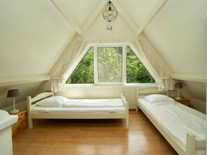 A bedroom with two single beds, a window with curtains, a hanging light fixture, and a wooden floor. - Holiday Home With 3 Bedrooms (Oostkapelle)