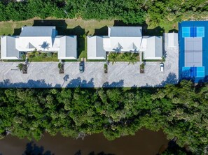A long building with a flat roof, surrounded by dense greenery and a body of water. - Seashells Unit 31 2 Bedroom Condo (Sanibel)