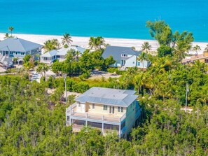 A coastal property with multiple houses, a beach, and dense greenery. - X1114 Schefflera Ct 4 Bedroom Home (Captiva)